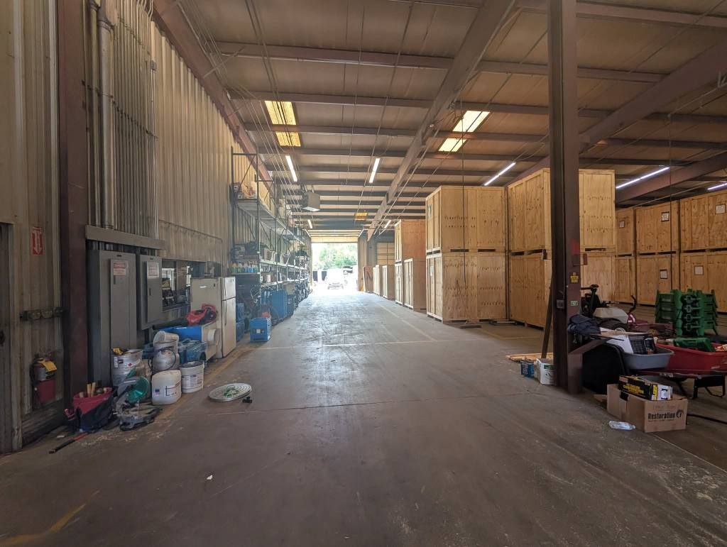 A wide-angle view of a warehouse aisle featuring large wooden shipping crates stacked on the right side.