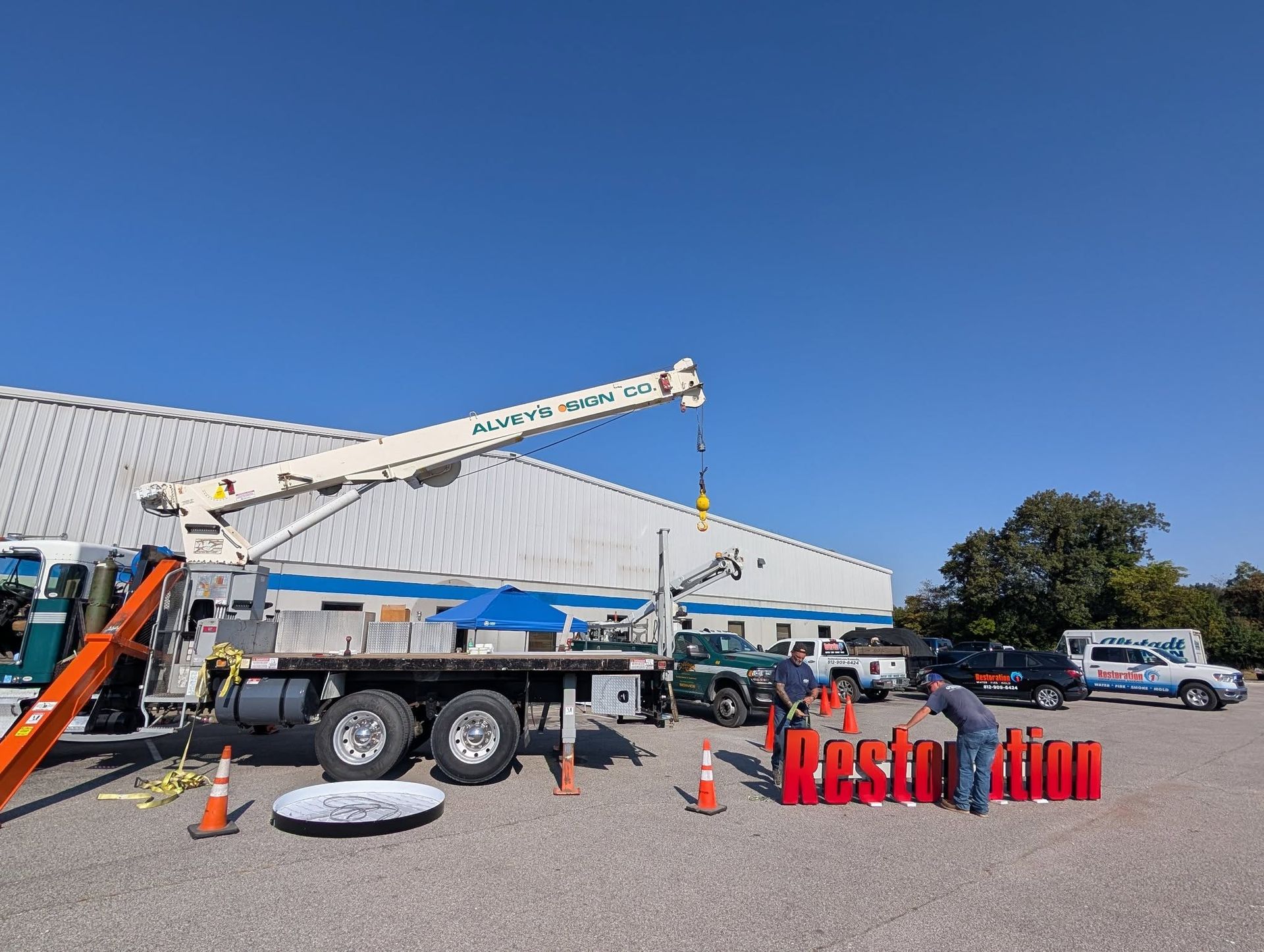A crane truck and two workers position large red 