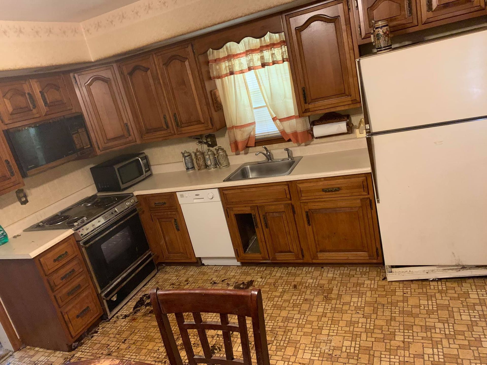 Kitchen with wooden cabinets, a white refrigerator, a stove, a sink, and patterned flooring.