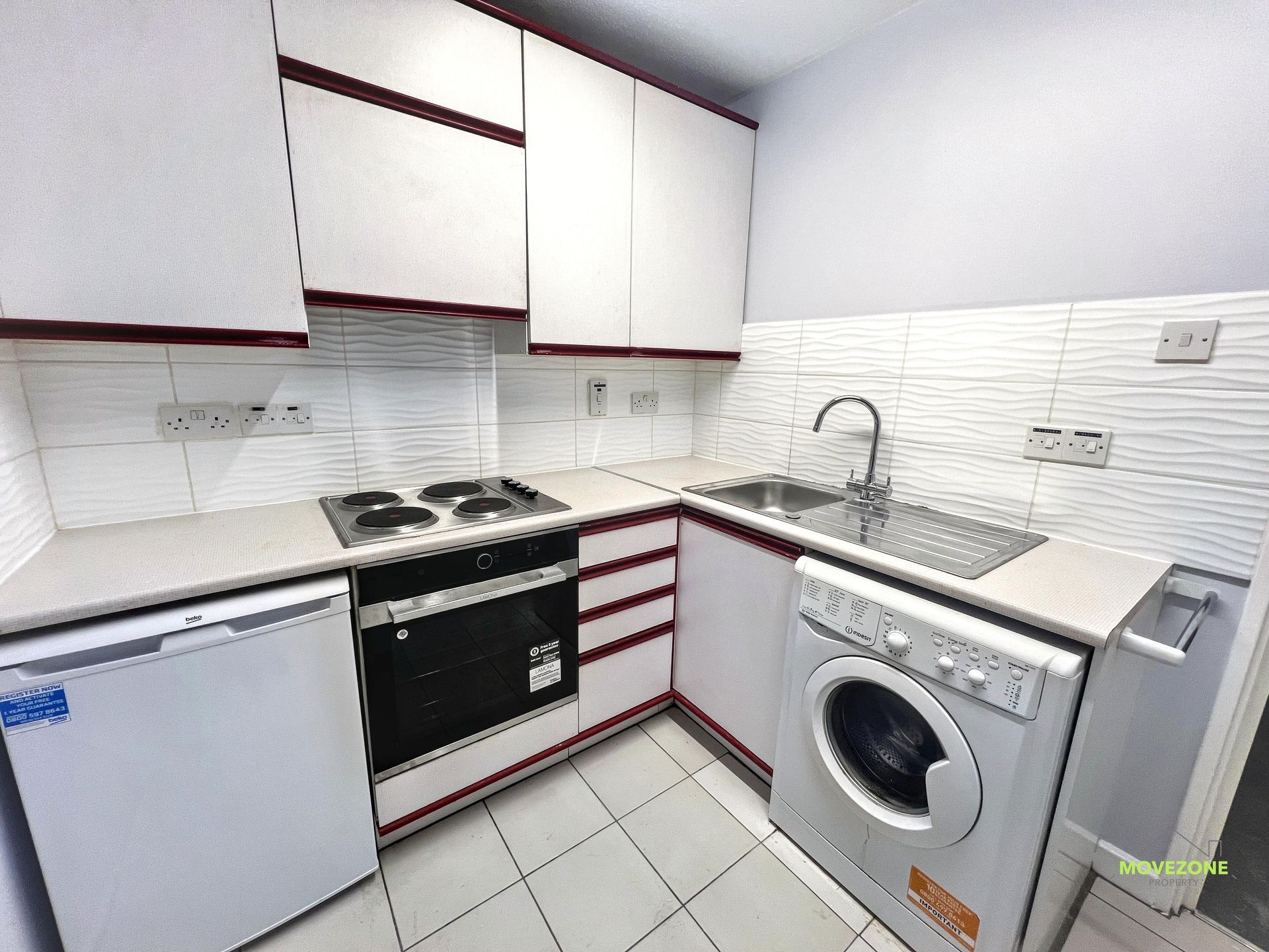 Compact white kitchen with black countertops, oven, dishwasher, sink, and washing machine.