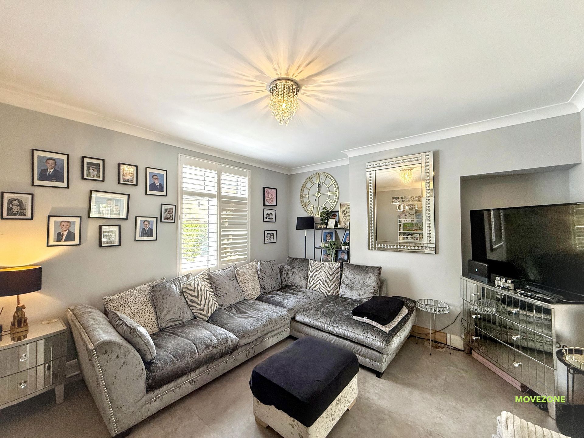 Bright living room with gray sectional sofa, wall gallery, mirror, TV, and beige carpet