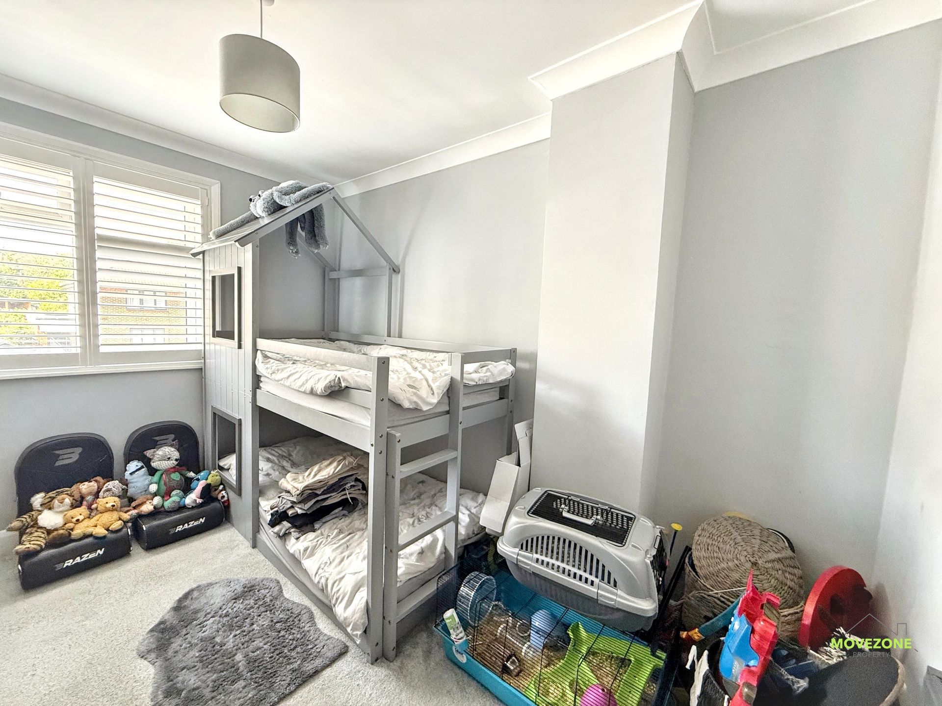 Children’s bedroom with gray bunk bed, toys, laundry baskets, and a window with blinds