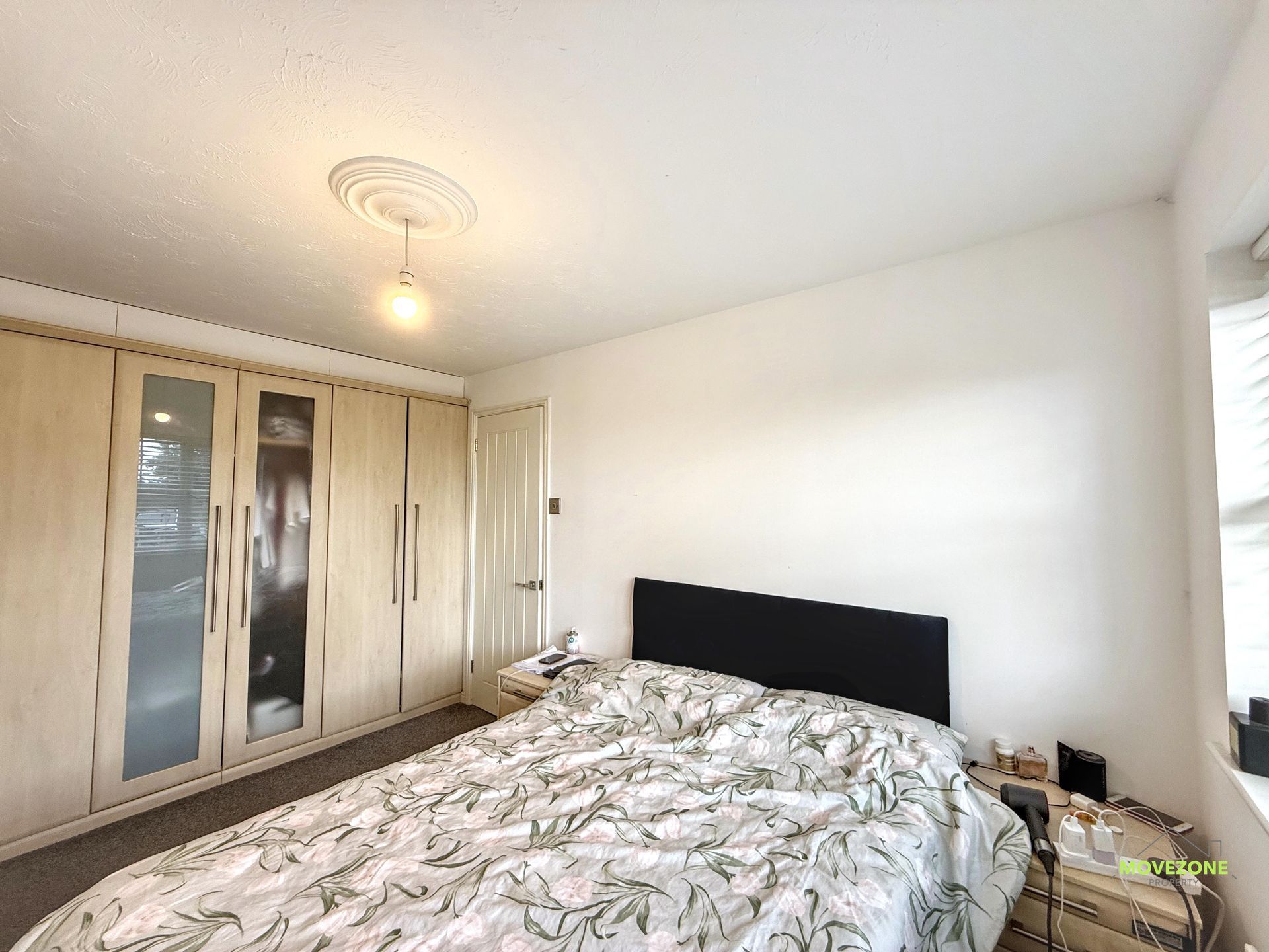 Bedroom with wardrobe, bed, and window in a bright, minimalist room
