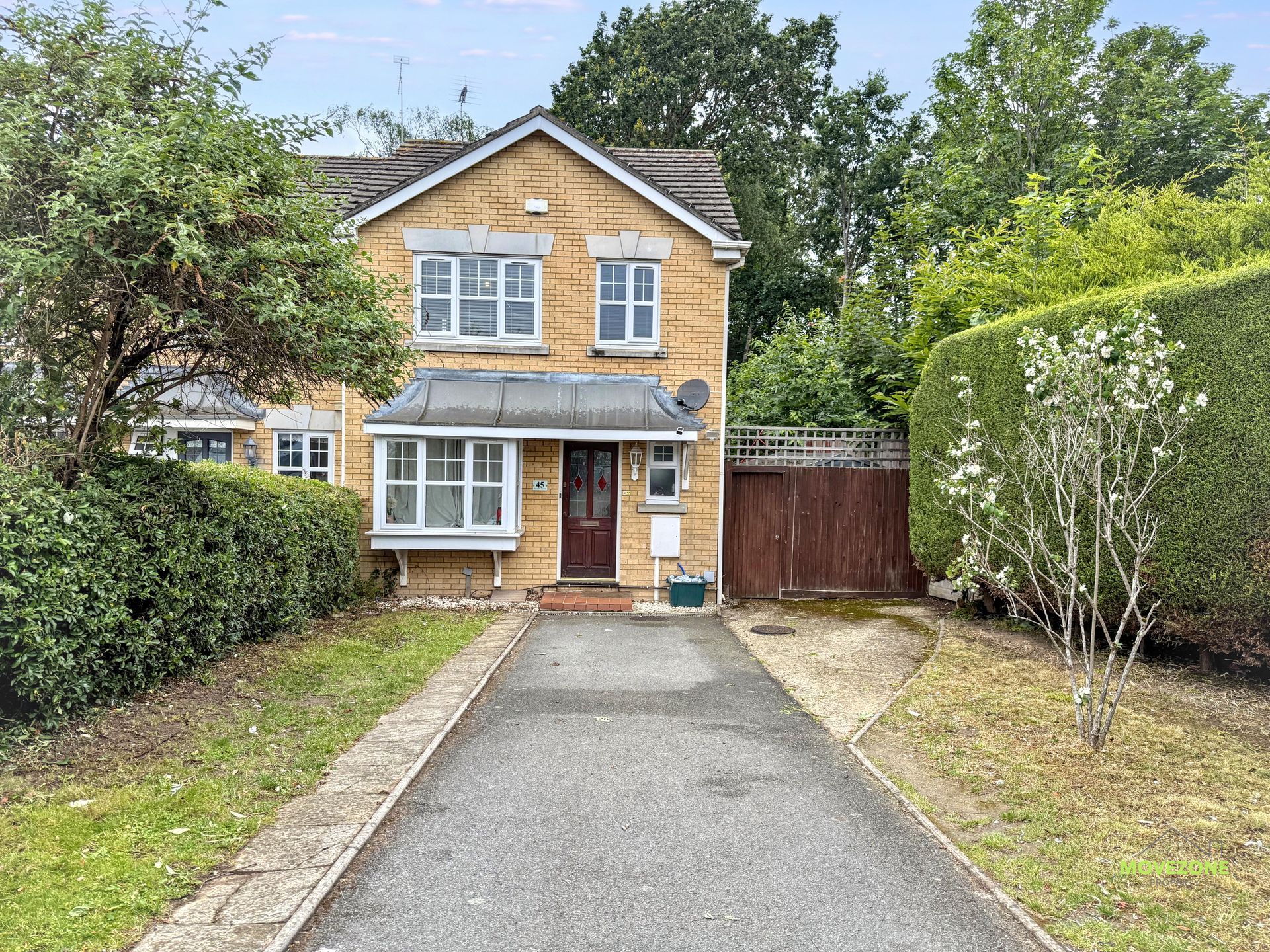Two-story brick house with driveway, front garden, and wooden side gate