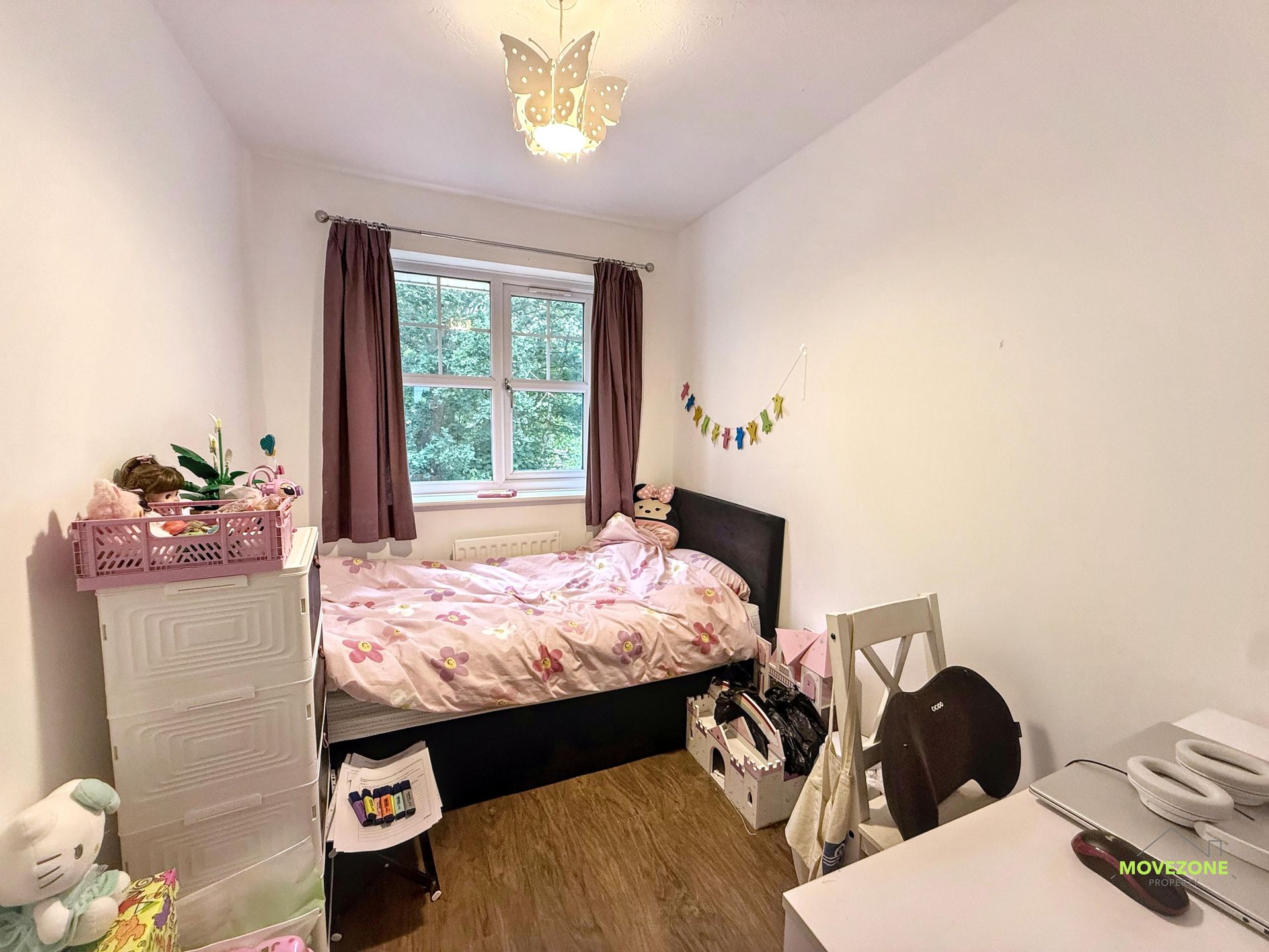Small bedroom with a single bed, window, toy bunny, and pink decor on white walls.
