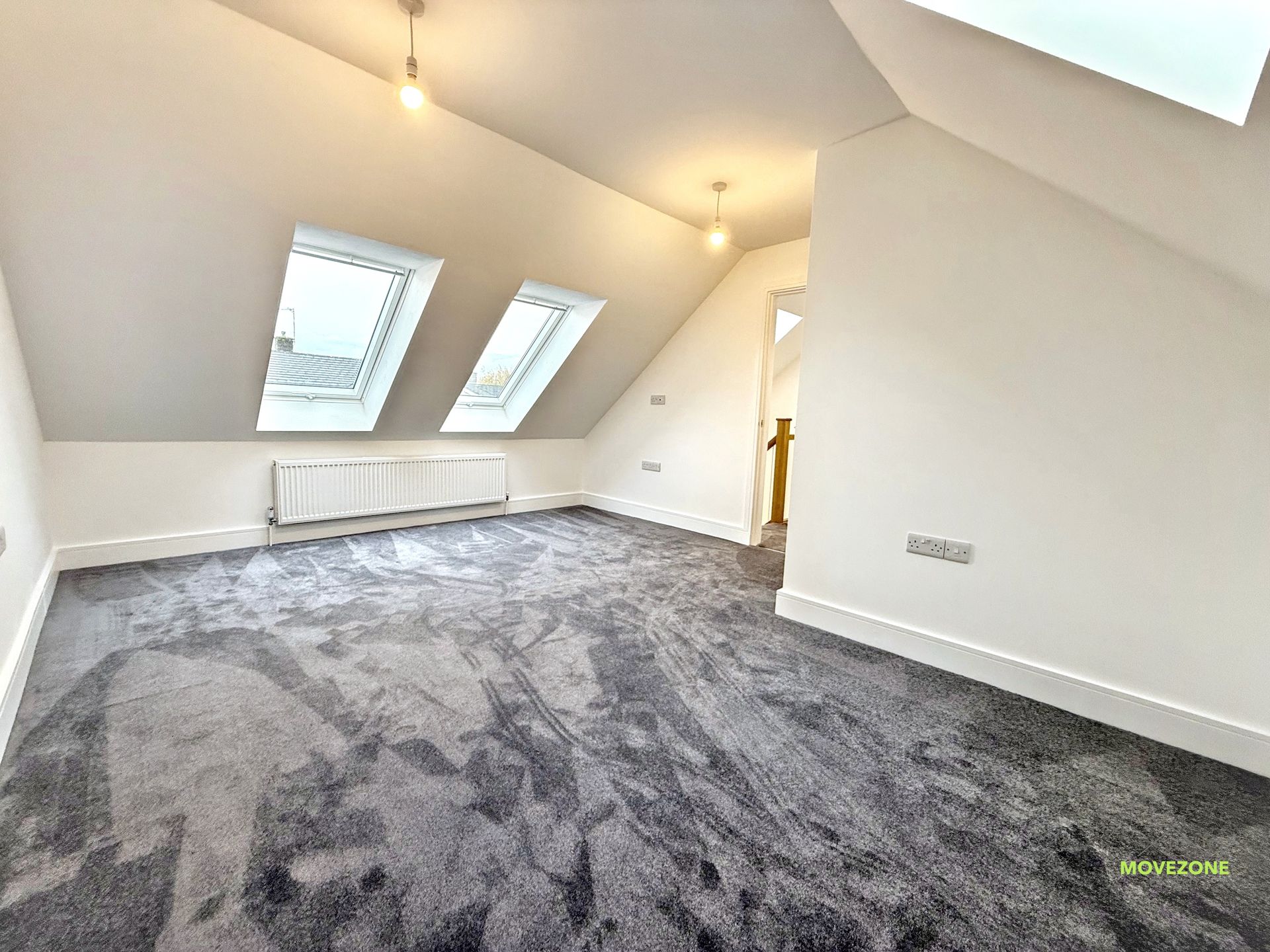 Empty attic room with gray carpet, white walls, skylights, and sloped ceiling.