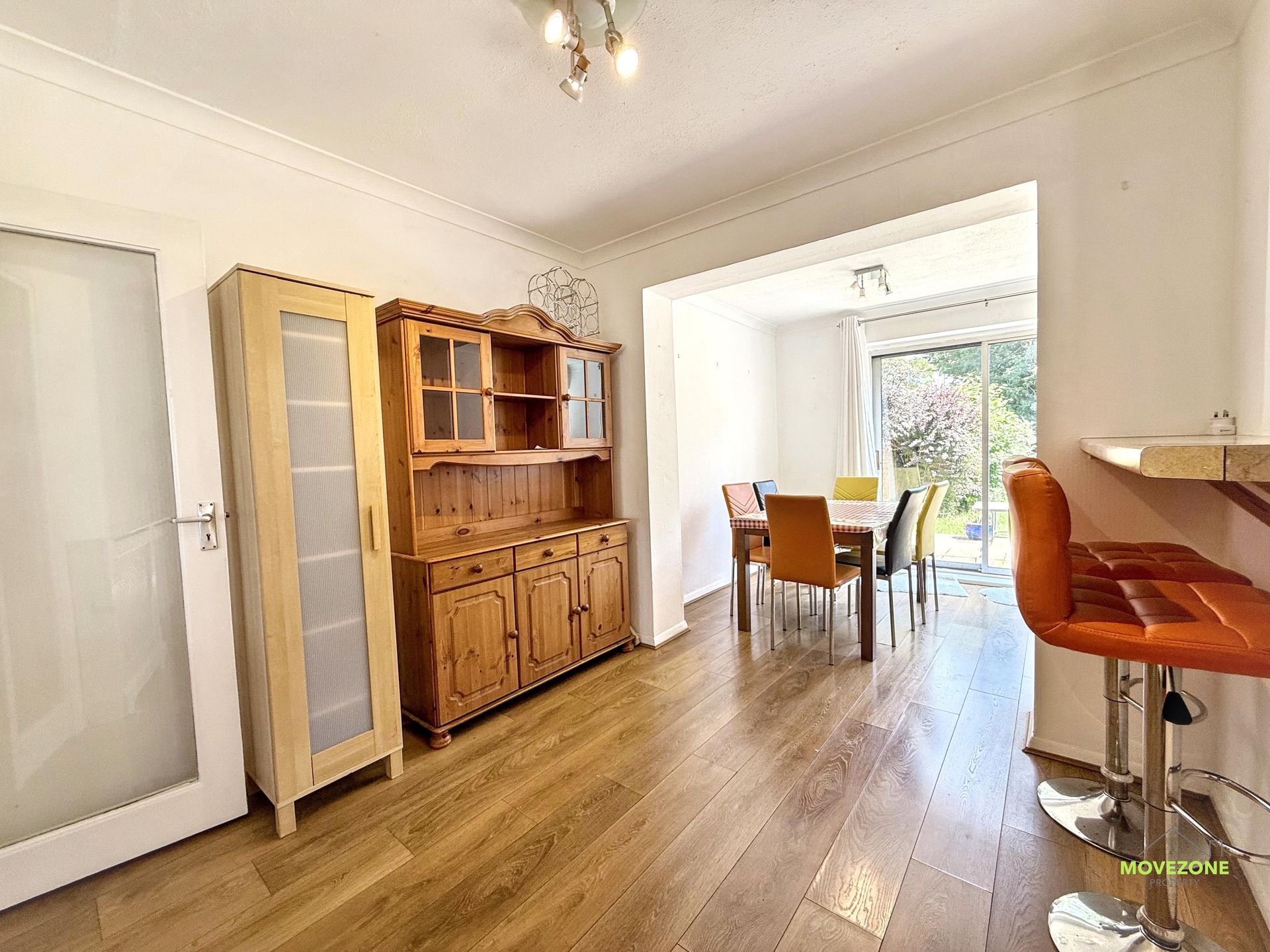 Bright dining room with wooden hutch, table, chairs, and large sliding glass doors to the garden