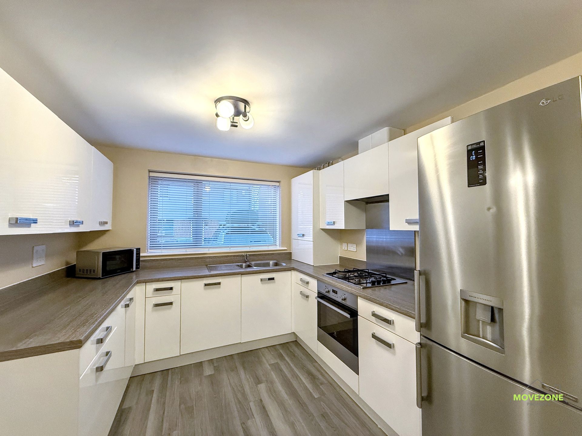 Bright modern kitchen with white cabinets, wood countertops, stainless steel appliances, and a window over the sink