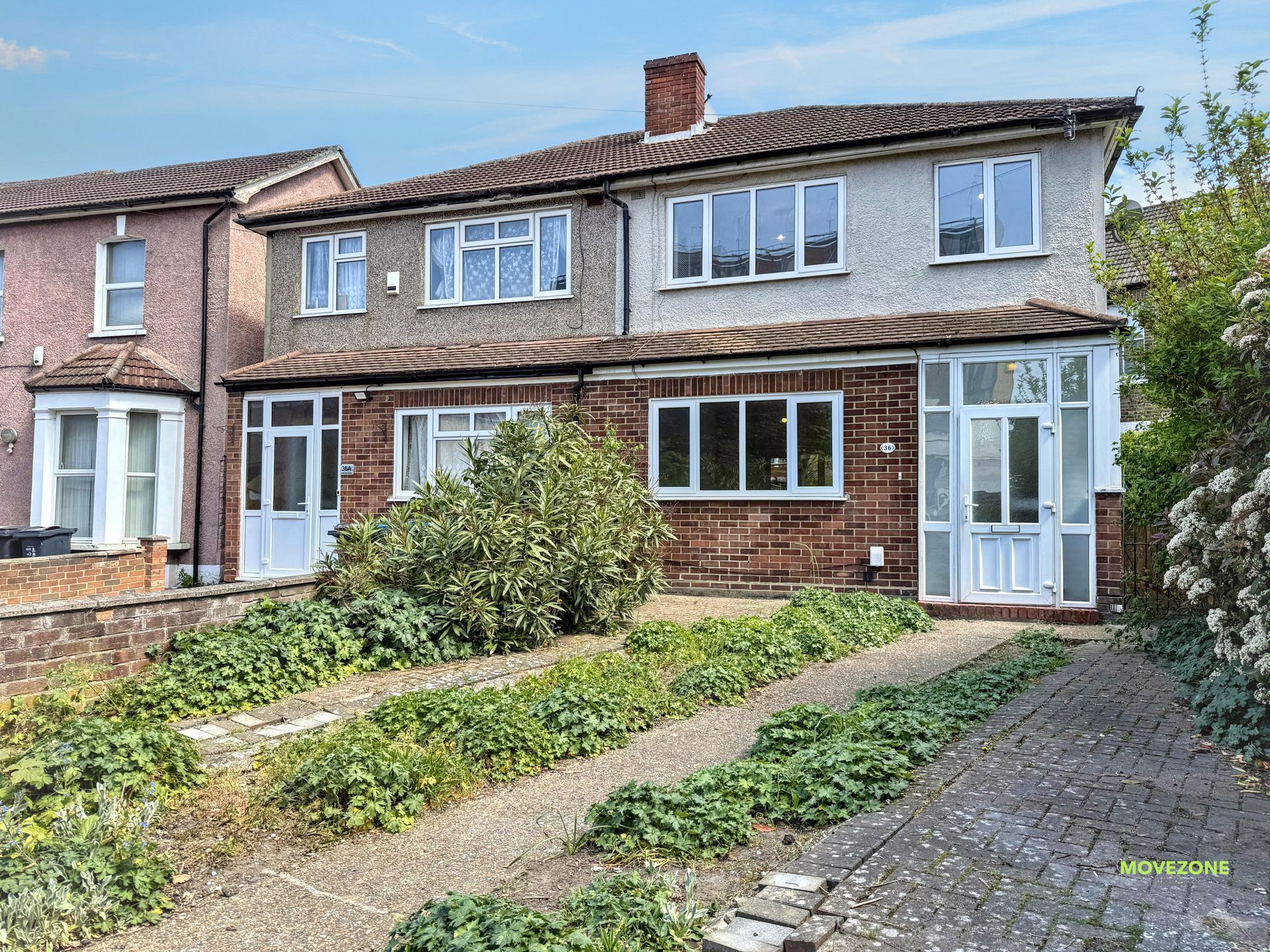 Semi-detached brick house with front garden, white-framed windows, and a paved path