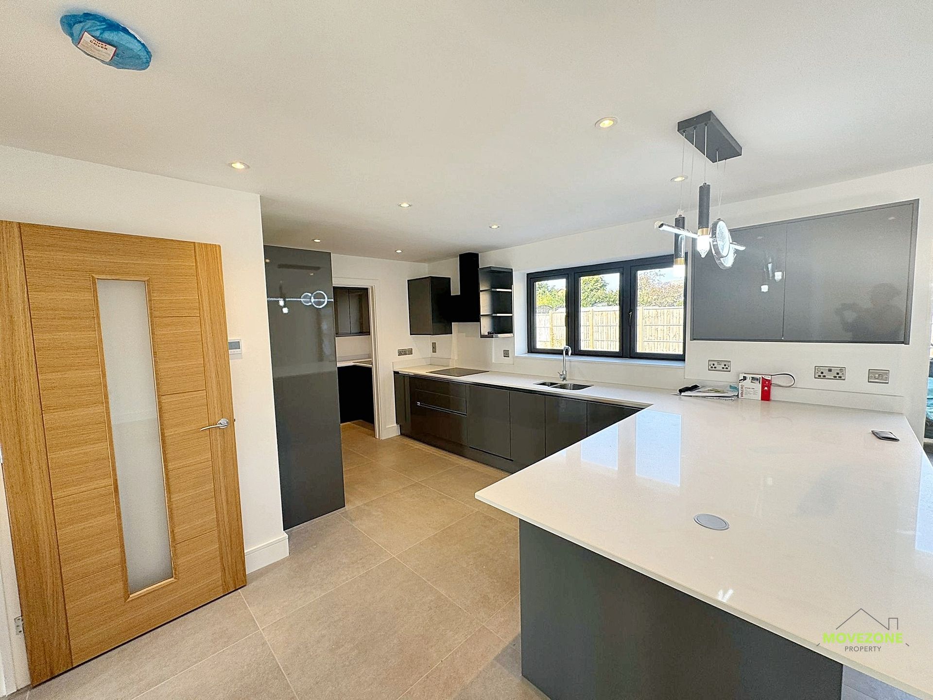 Modern kitchen with white island, dark cabinets, wood floor, and large windows