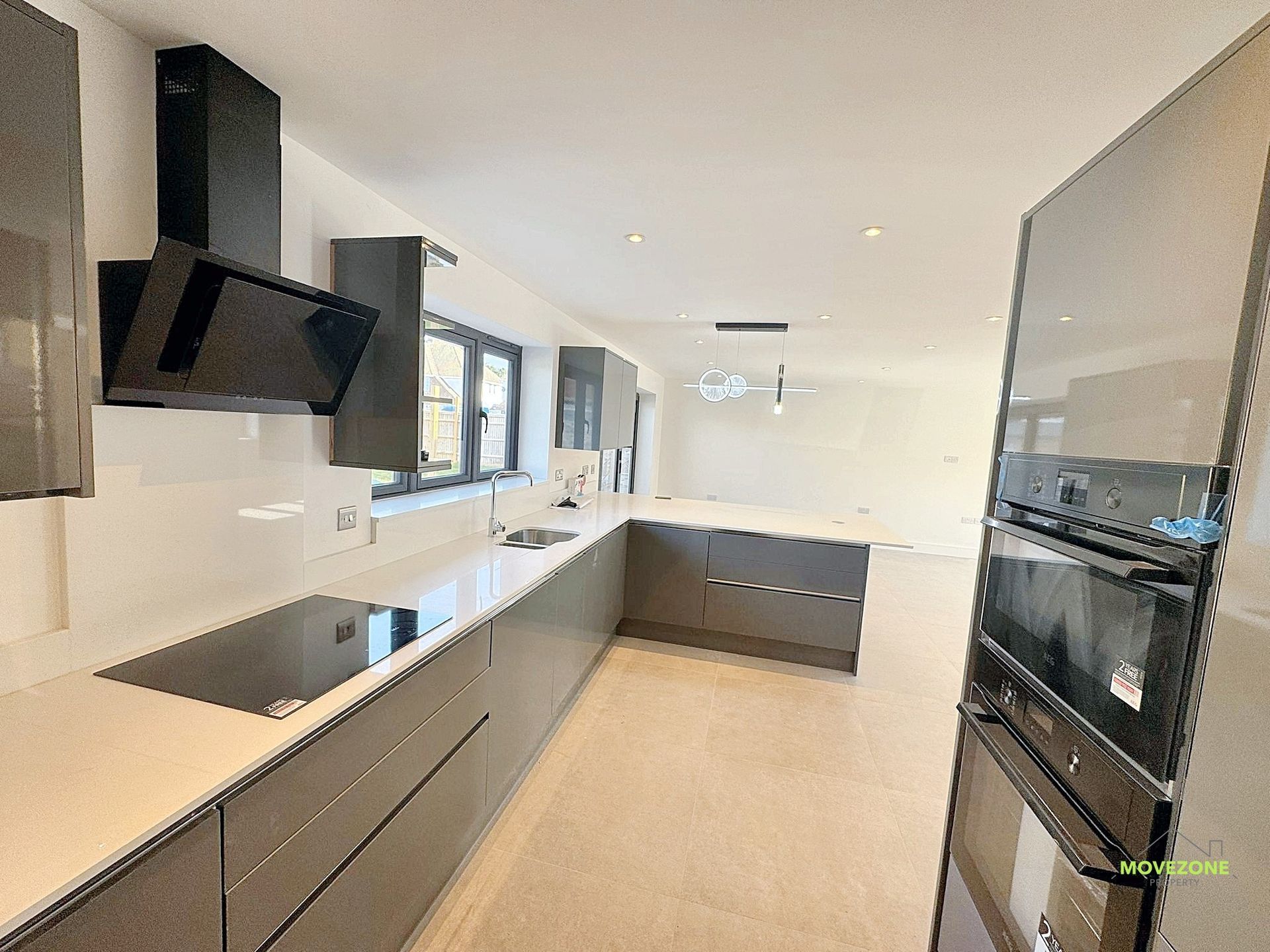 Modern kitchen with dark cabinets, white countertops, and built-in appliances in a bright, airy room