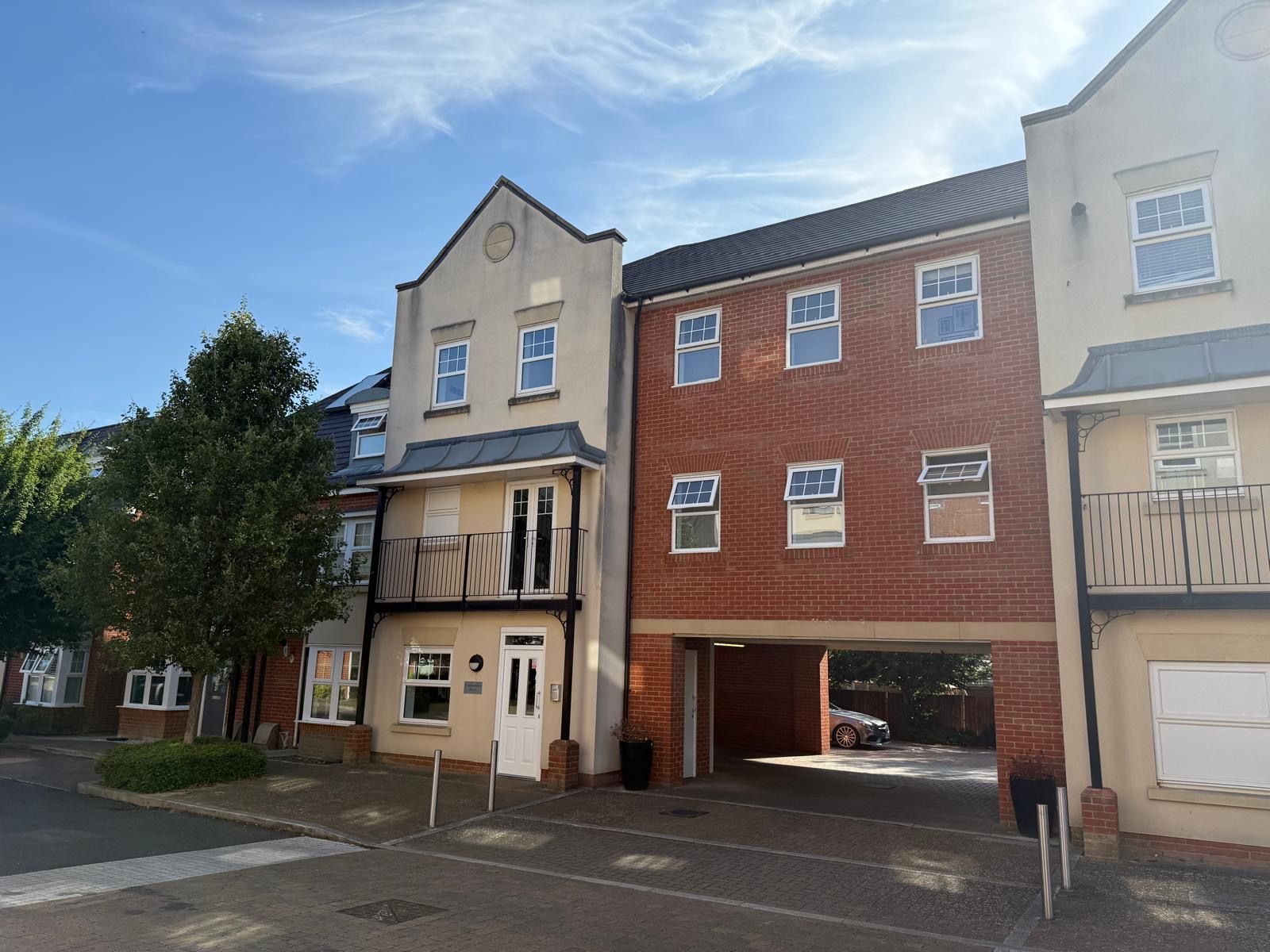 Row of modern brick townhouses with parking bays under a blue sky