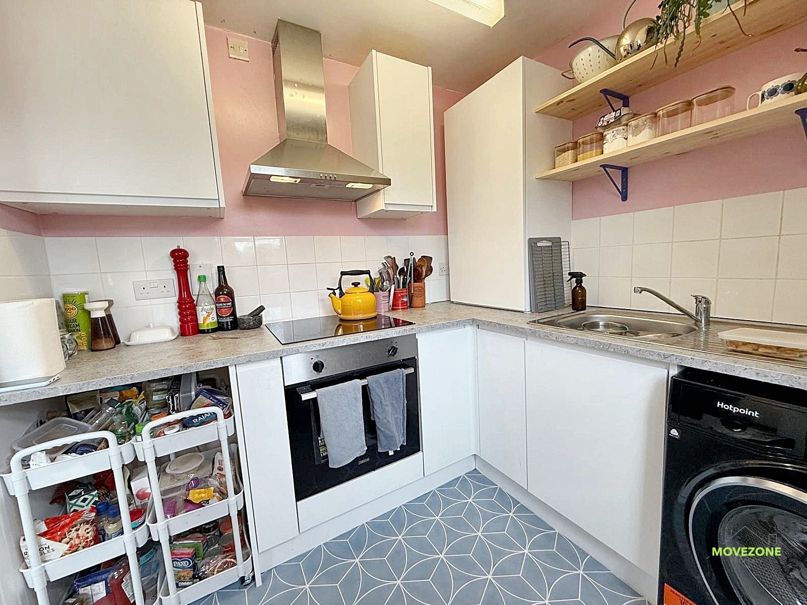 Pink and white kitchen with gray patterned floor, white cabinets, and open shelving