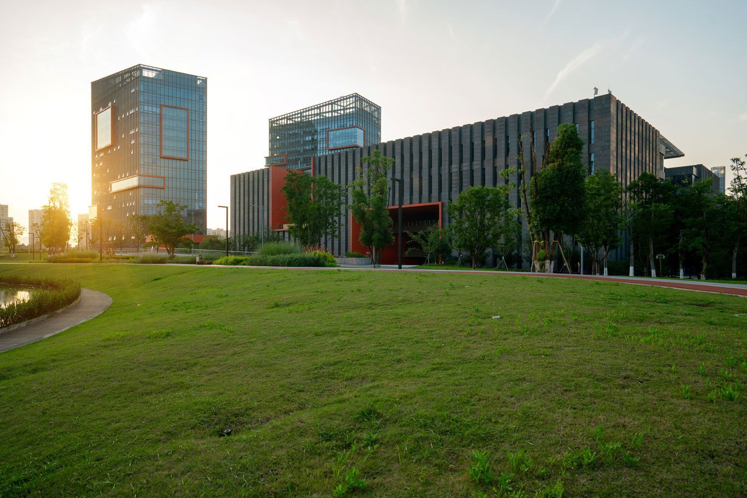 Modern office buildings beside a large green lawn at sunset