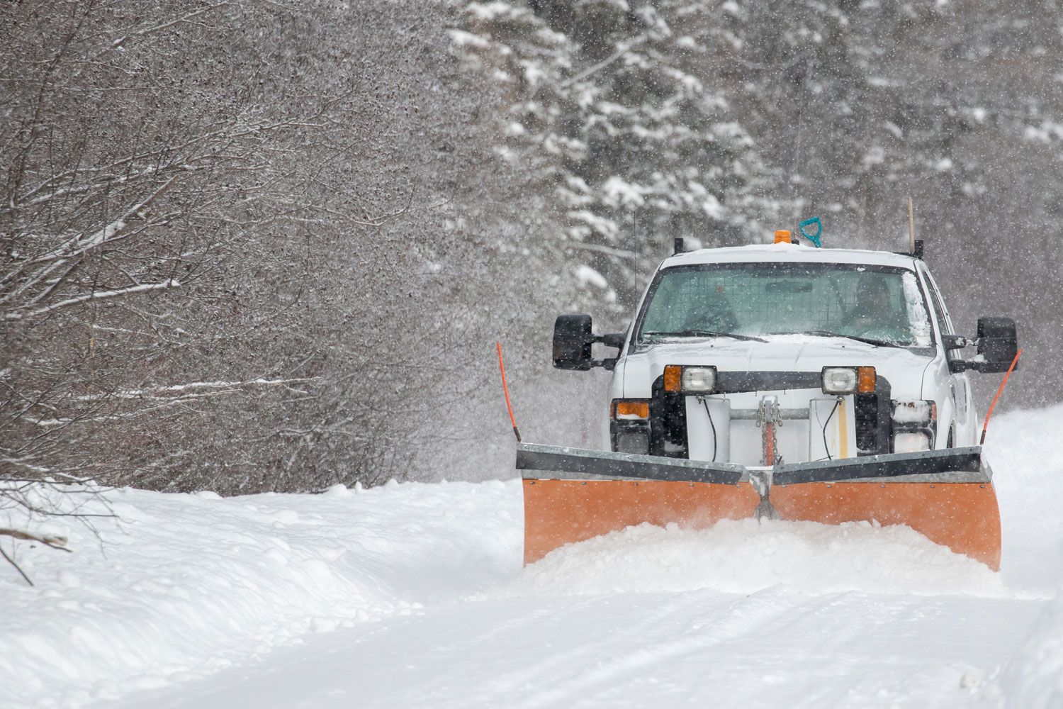 Snowplow clearing a snowy road in a heavy snowfall