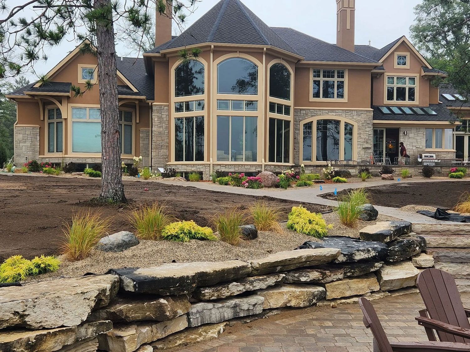 Large stone-and-stucco house with landscaped yard and tiered retaining wall