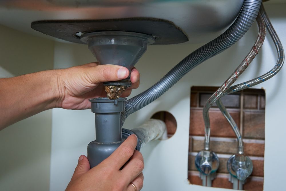 Hands Working on a Sink Drain Assembly — Gibson Plumbing & Roofing Pty Ltd in Gladstone, QLD