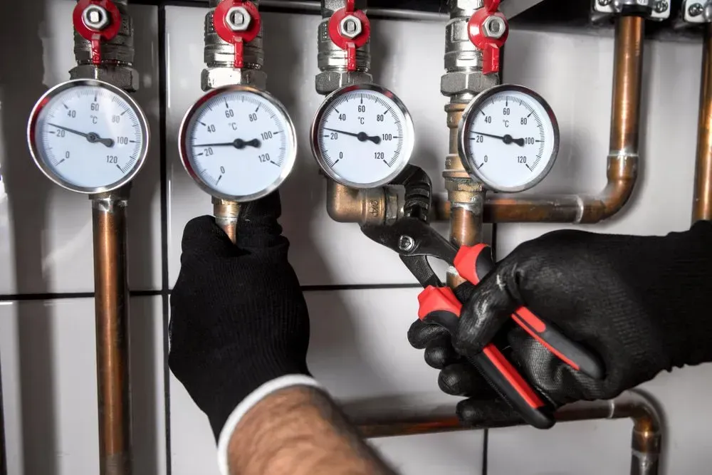 Plumber in Gloves Using Pliers to Adjust Plumbing System — Gibson Plumbing & Roofing Pty Ltd in Gladstone Central, QLD