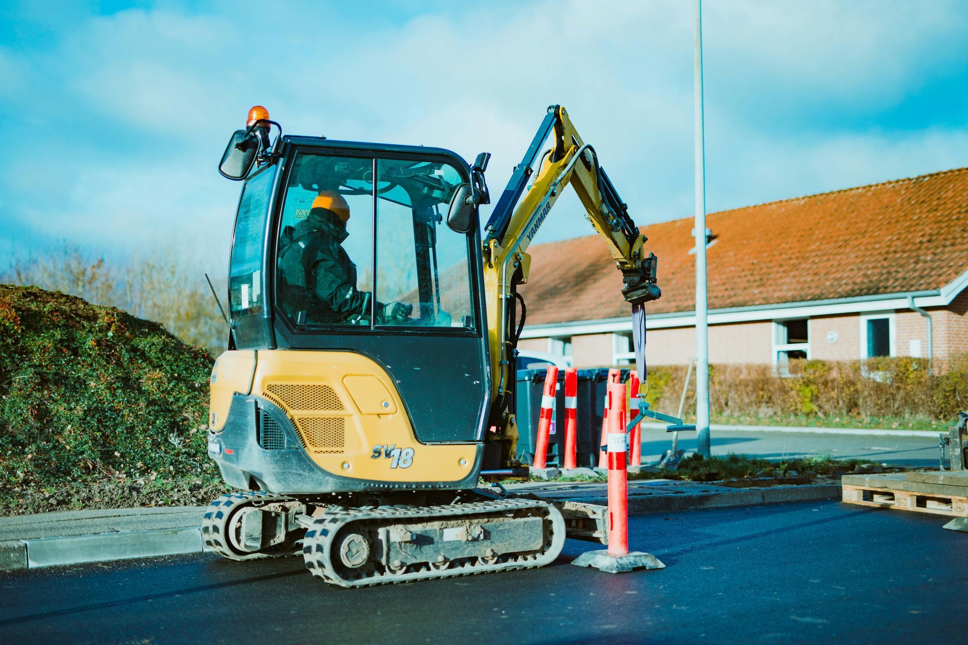 Mini excavator digging up roadside shrubs