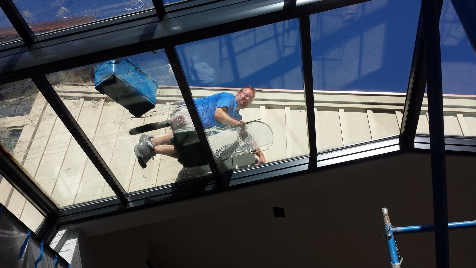 A man in a blue shirt is cleaning a window | Champaign, IL | Precision Maintenance