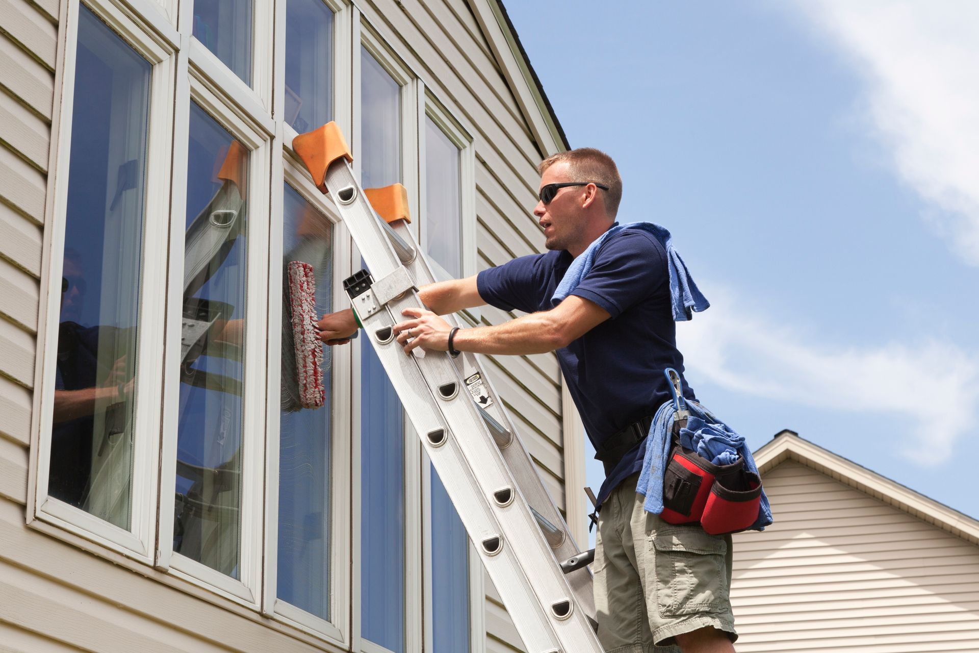 Man Standing on the Ladder Cleaning a Window — Champaign, IL — Precision Maintenance