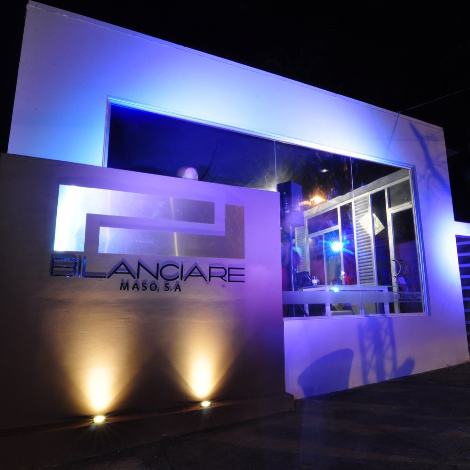 Exterior de edificio moderno por la noche con iluminación de acento azul, letrero iluminado que dice