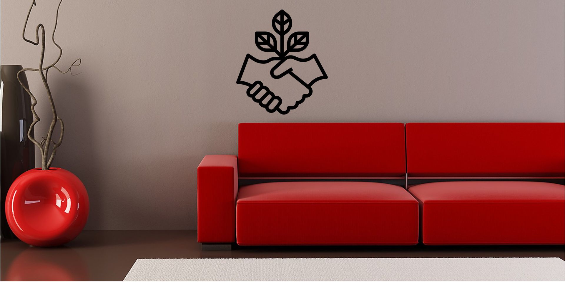 Un sofá de color rojo brillante se encuentra contra una pared lisa, junto a un jarrón circular rojo a juego con ramas decorativas.