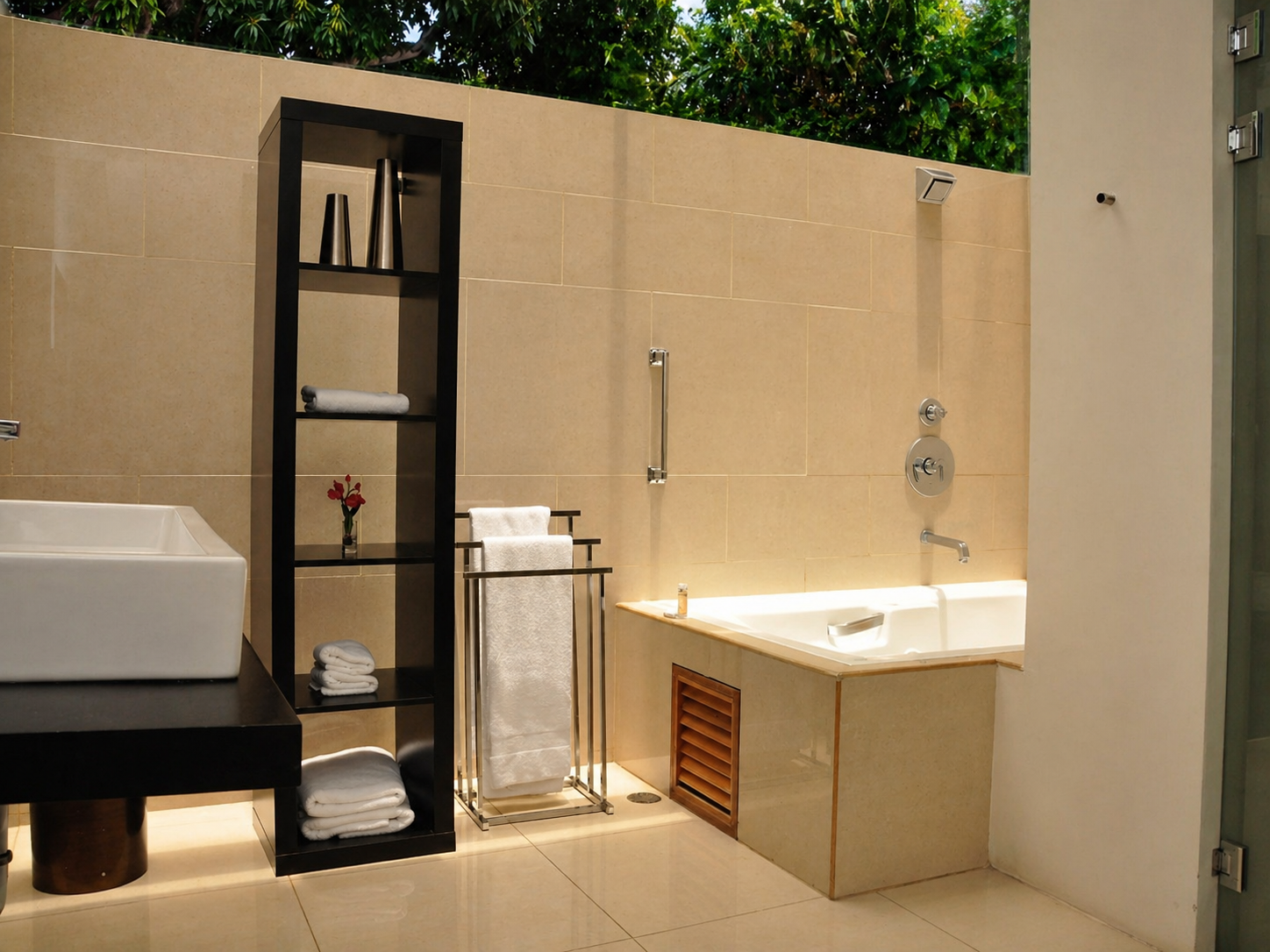 Un baño moderno con lavabo sobre encimera, estantería alta, toallero y bañera empotrada revestida de azulejos.