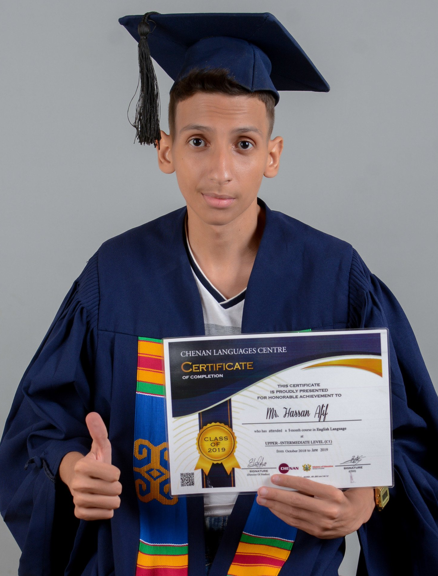 Personne en toge de remise de diplôme tenant un certificat et levant le pouce.