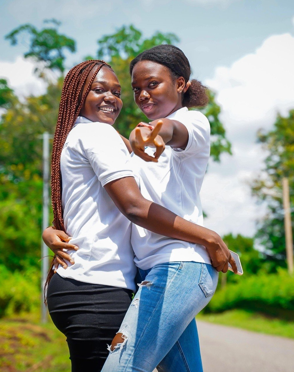 Deux jeunes femmes s'embrassent et pointent vers la caméra.