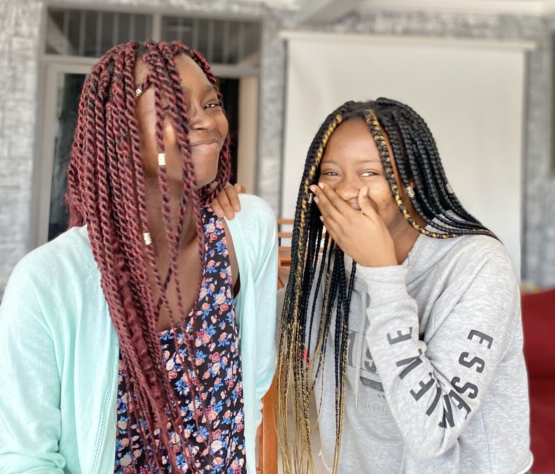 Deux apprenantes de Chenan Africa avec des tresses se tiennent l'une à côté de l'autre et l'une porte un sweat-shirt qui dit essex