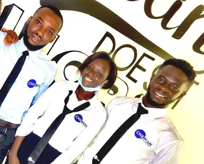 Trois personnes portant des cravates bleues et noires posent pour la photo. Logo « CHINAN » visible. Fond clair.