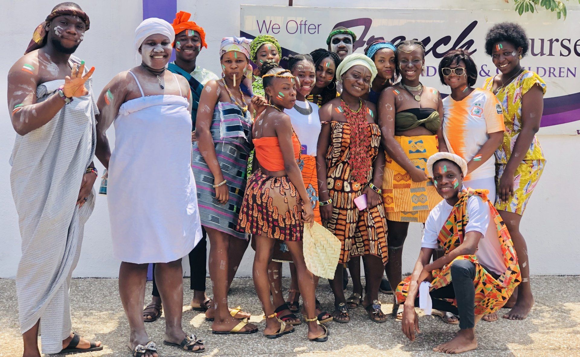 Groupe de personnes, dont beaucoup portent des tenues traditionnelles africaines colorées, posant en extérieur.