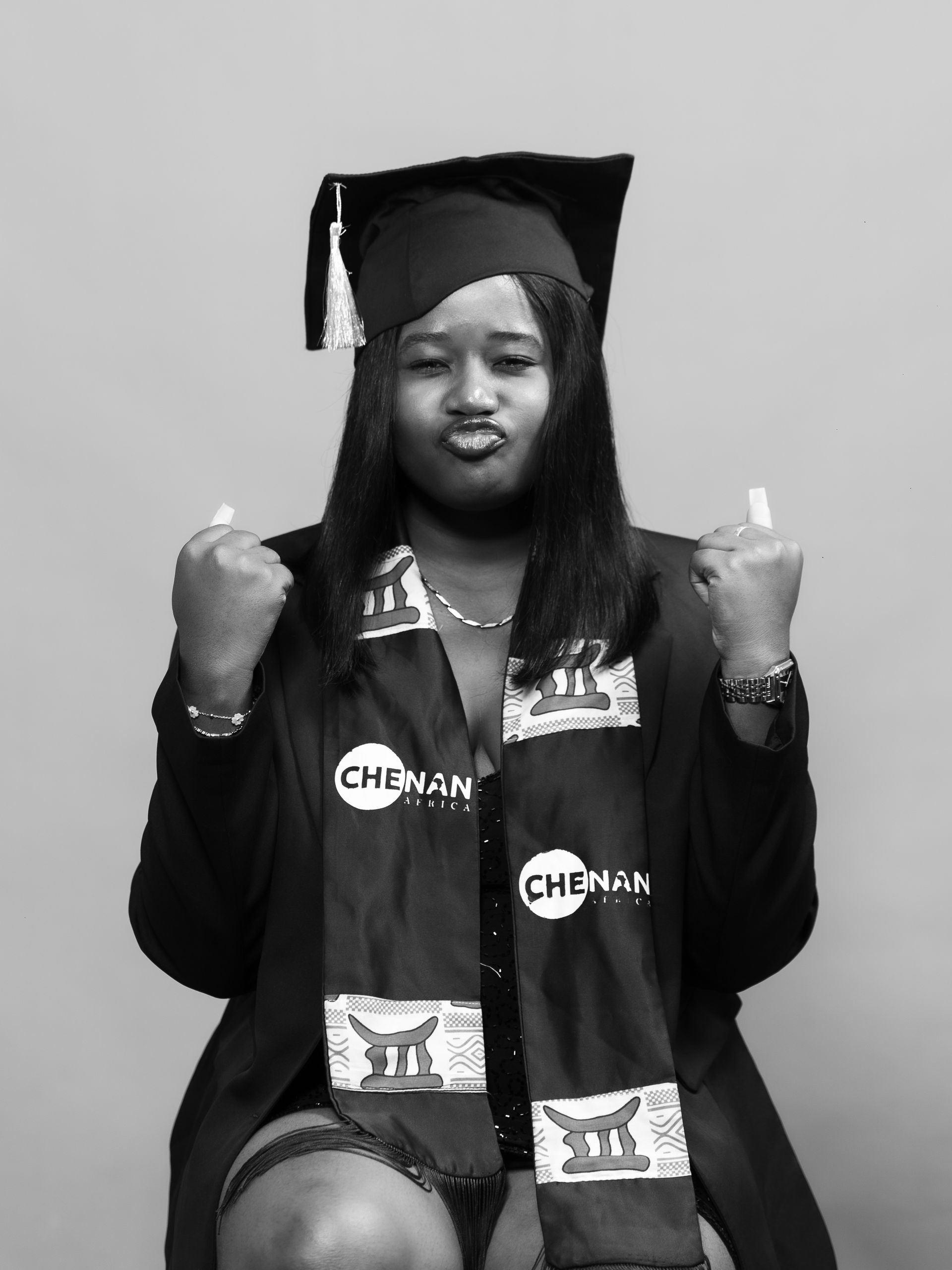 Personne en toque et robe de remise de diplôme, faisant une grimace et gesticulant des deux mains.