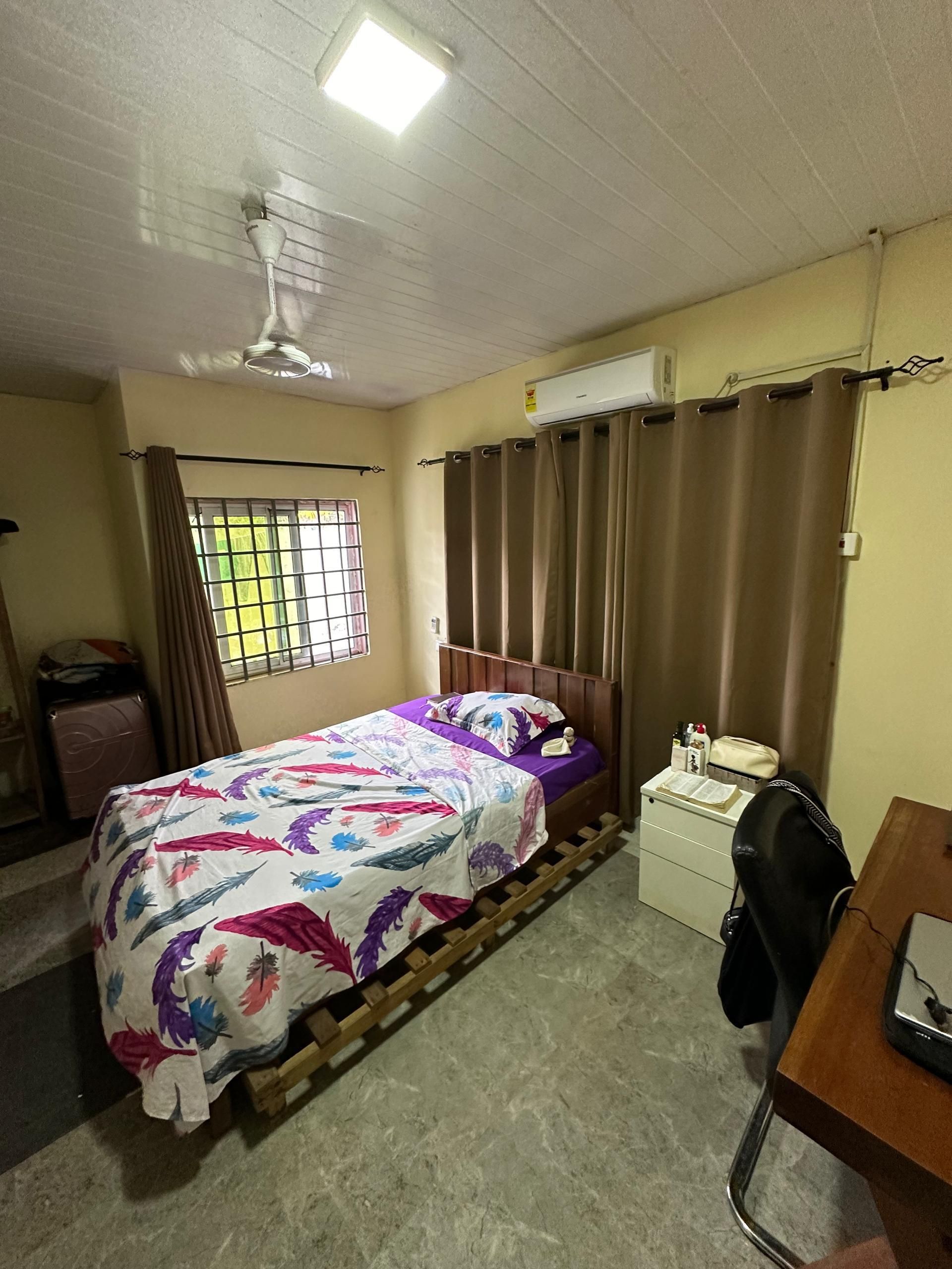 Chambre avec lit, bureau et rideaux. Murs et plafond de couleur claire.