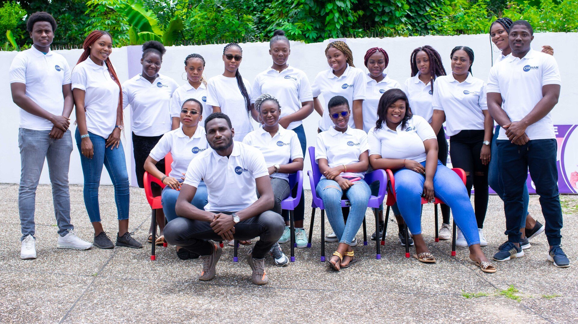Groupe de personnes en chemises blanches et jeans, posant en extérieur.