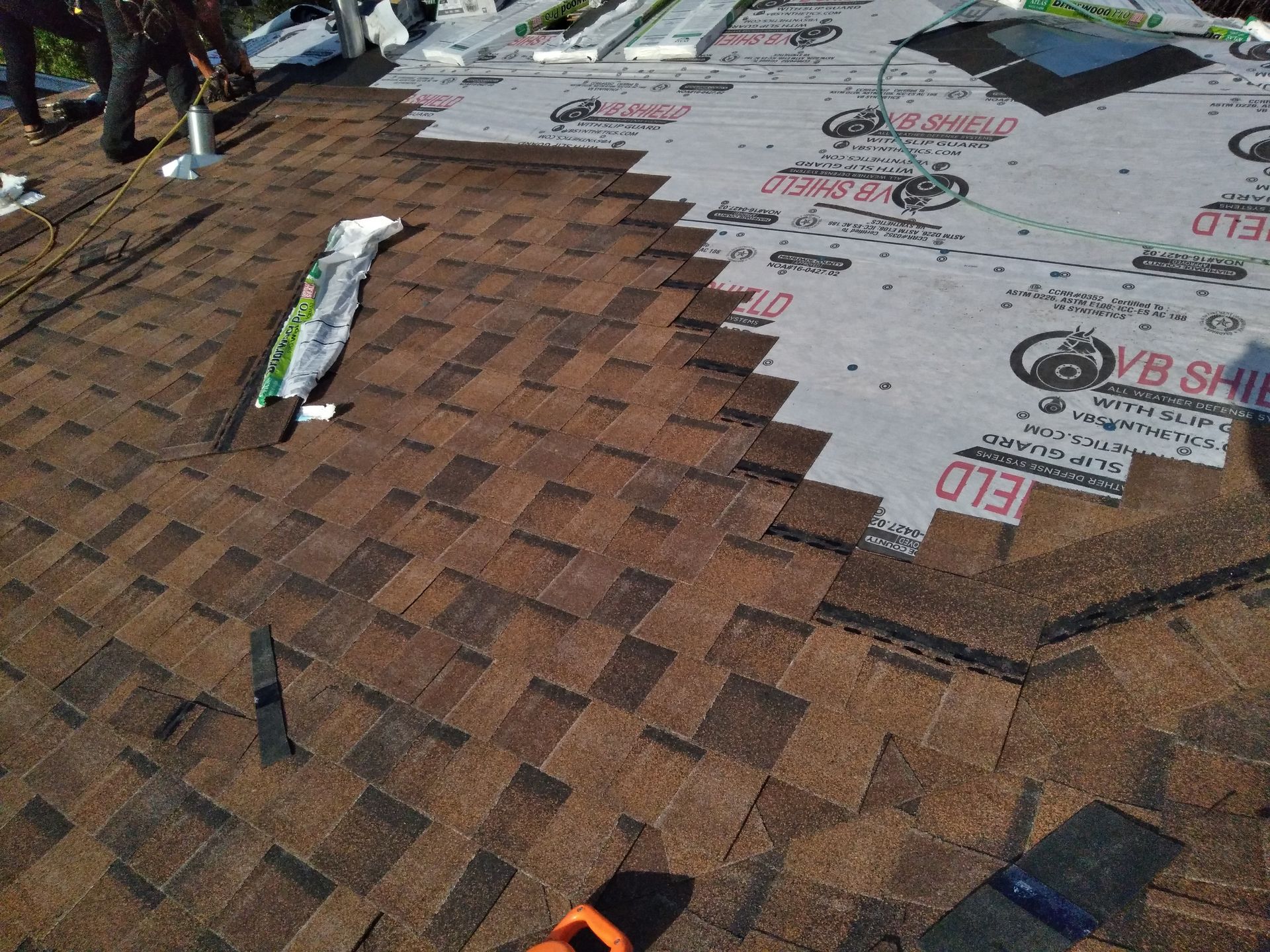 Roofers in Hillsboro, North Dakota installing composite asphalt shingles in a stair step pattern with six nails per shingle