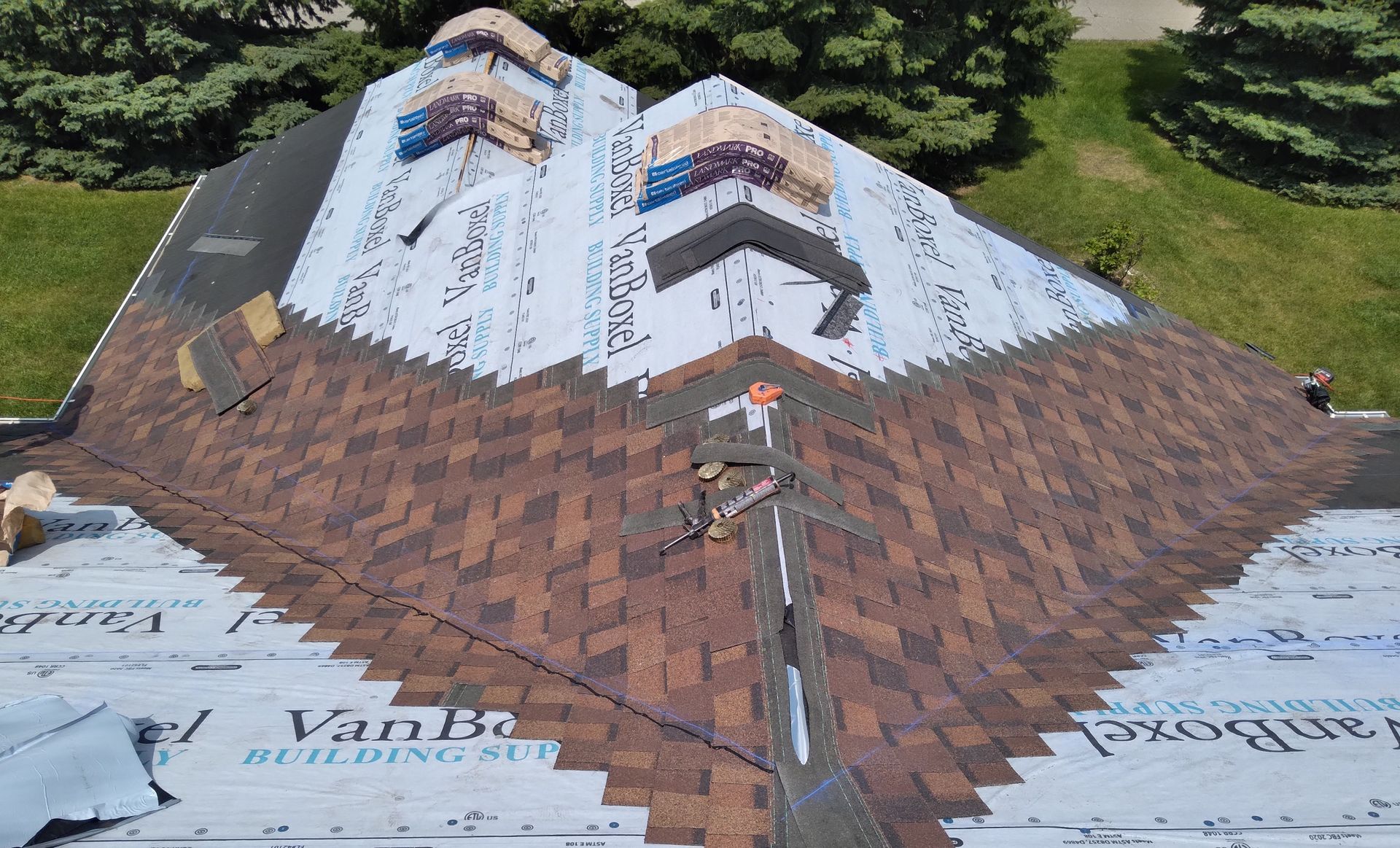 Bundles of shingles placed on roof ridge with underlayment installed on roof with two shingled valleys in Wahpeton, ND