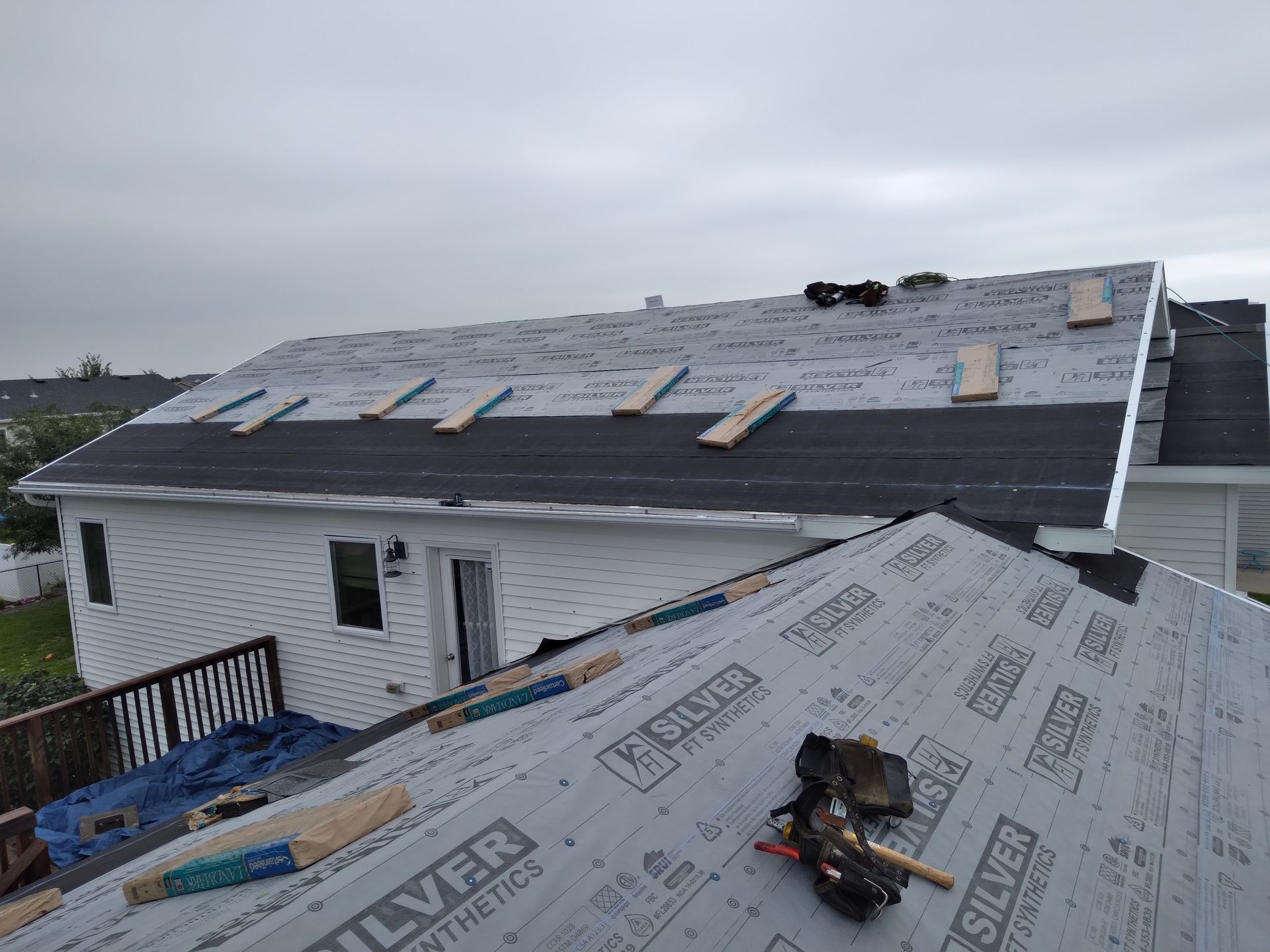 Two rows of ice and water guard at eave of roof, synthetic felt and bundles of pewter landmark shingles in Hillsboro, ND