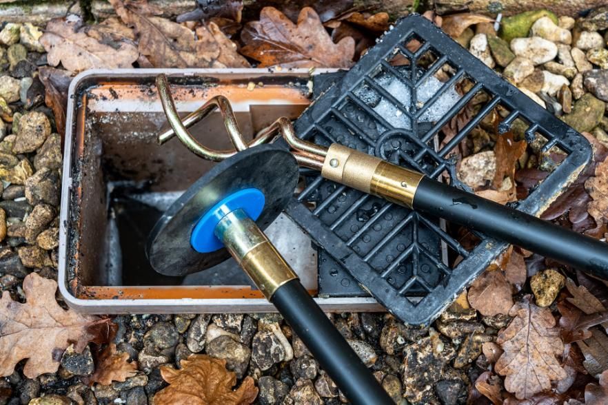 Drainage Cleaning Tools With Plunger And Snake In Gravel Setting — BJG Plumbing in Coolamon, NSW