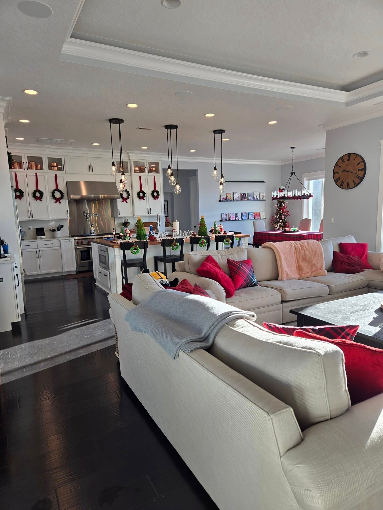 Open-concept living room and kitchen decorated for Christmas with a large beige sectional sofa and a breakfast bar.