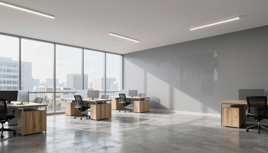Bright modern office with large windows, wooden desks, chairs, and sunlight on polished concrete floor