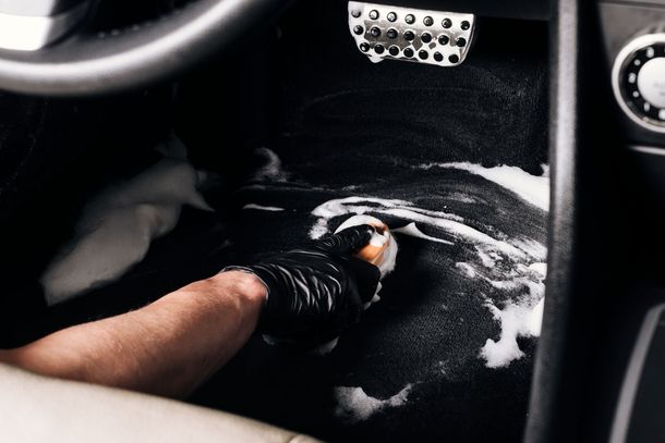 A person is cleaning the interior of a car with a sponge.