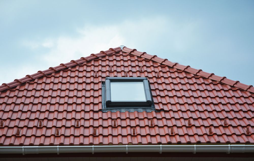 A red tiled roof with a skylight on top of it.