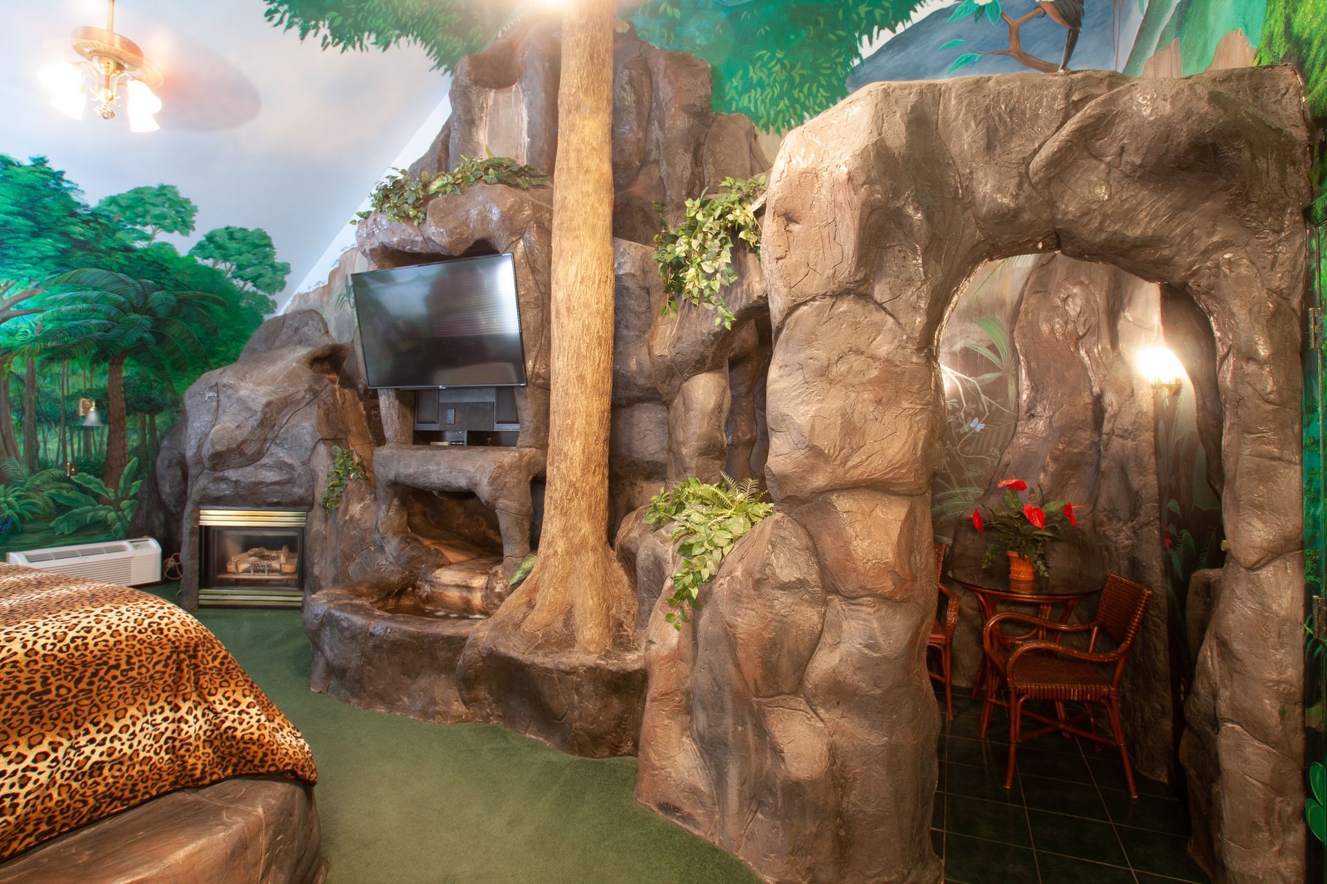 A bedroom with a fireplace and a tree in the corner