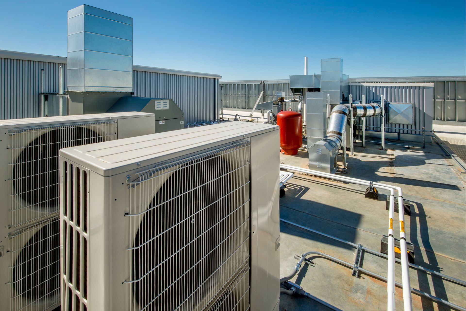 There are a lot of air conditioners on the roof of a building.
