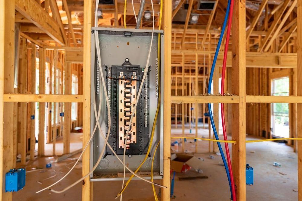 Wooden-framed home under construction with electrical panel and wiring visible.