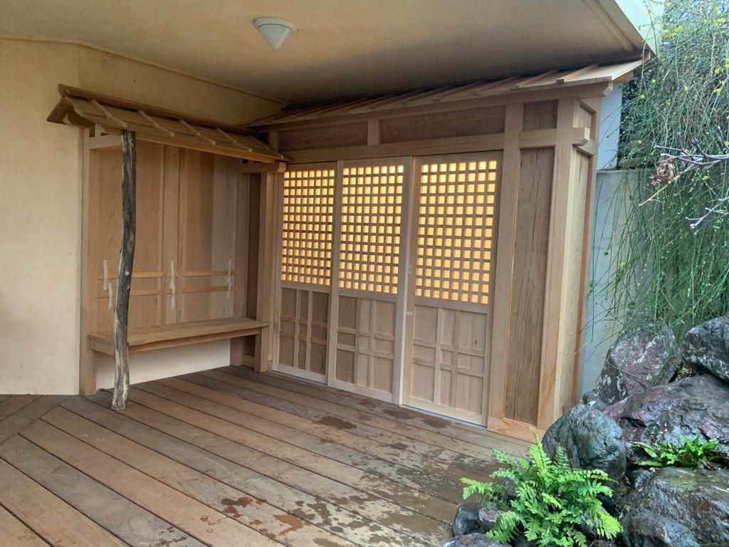 Een houten veranda met schuifdeuren en een bankje.