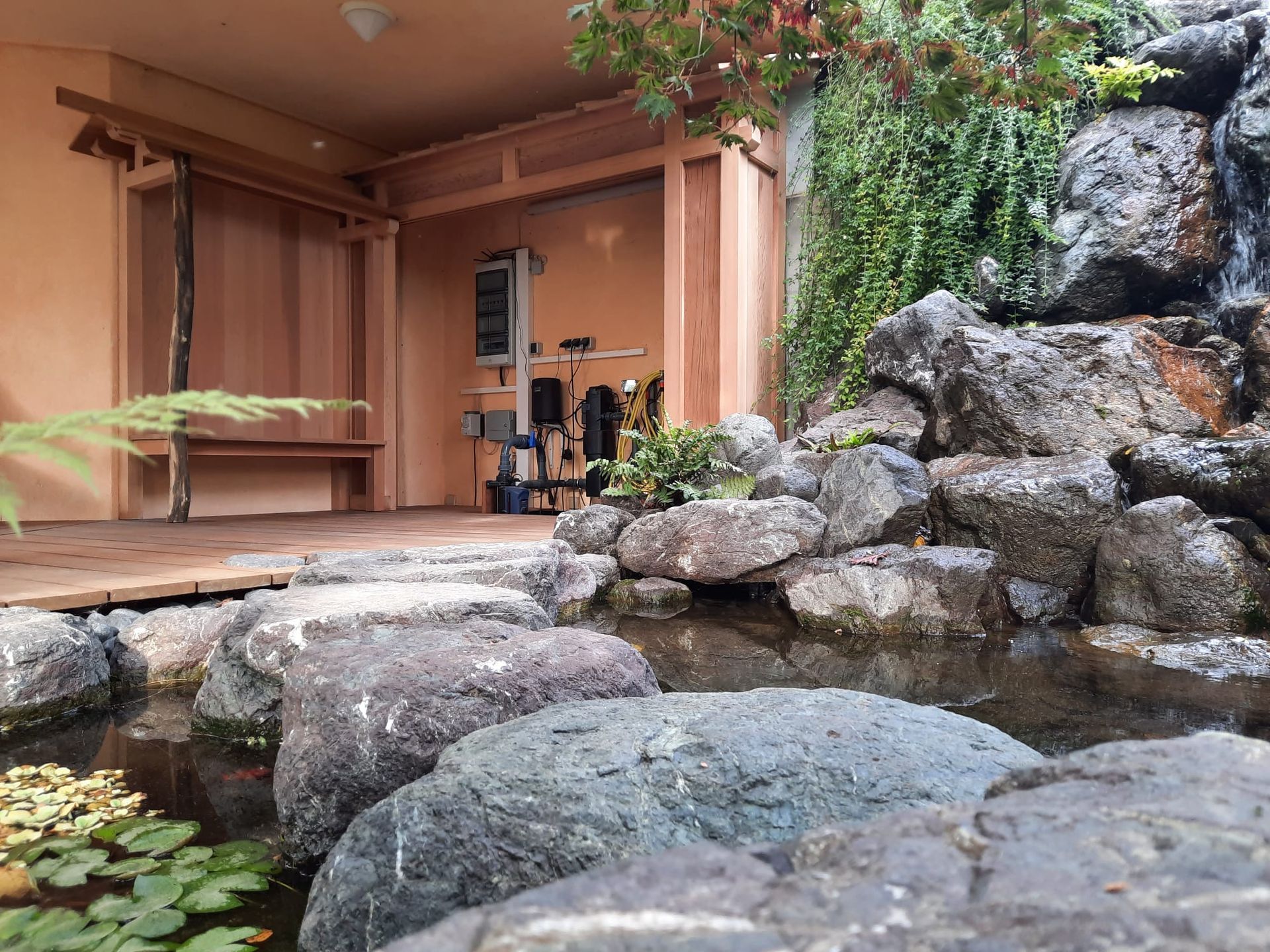 Een huis met een vijver en een waterval ervoor.