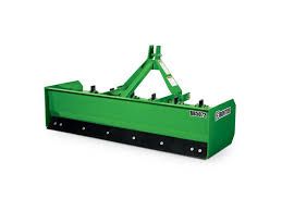 a green tractor blade is sitting on top of a white surface .